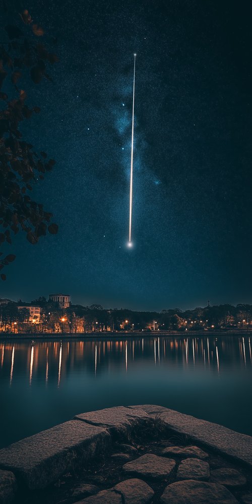 A meteor is seen over a lake at night wallpaper